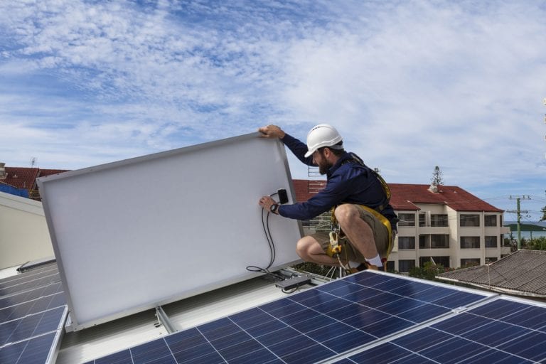 Contstruction worker in hard hat installs solar panel